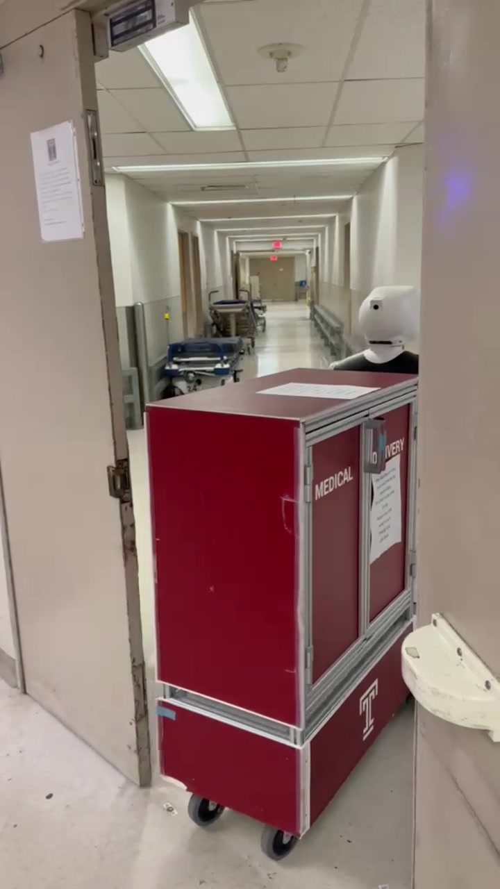 Gary entering a hospital corridor with a medical delivery cart